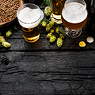 hops and glasses full of beer on a wooden table