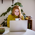 woman drinking coffee and looking at laptop screen