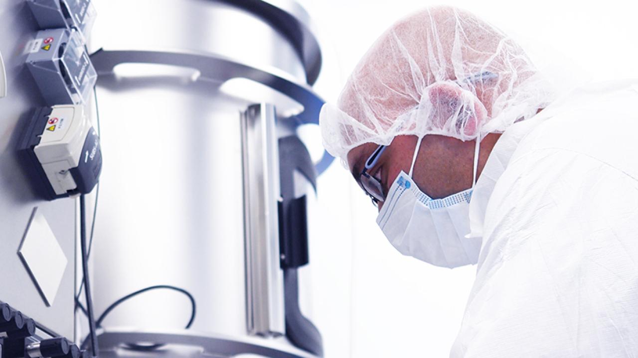 man wearing PPE examining lab equipment