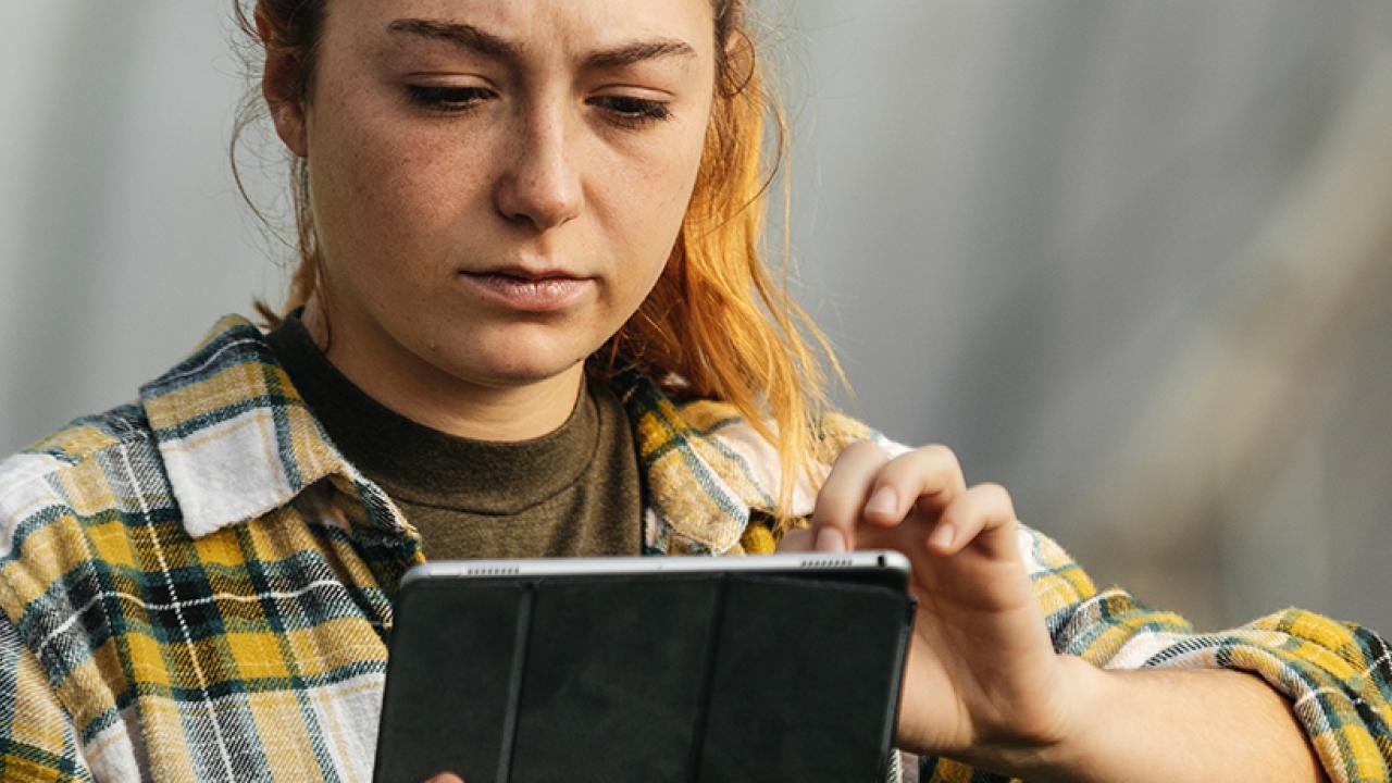 woman working on a tablet in a greenhouse