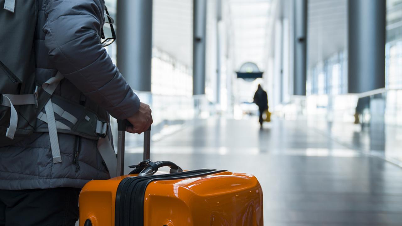 Man wheeling suitcase in airport terminal