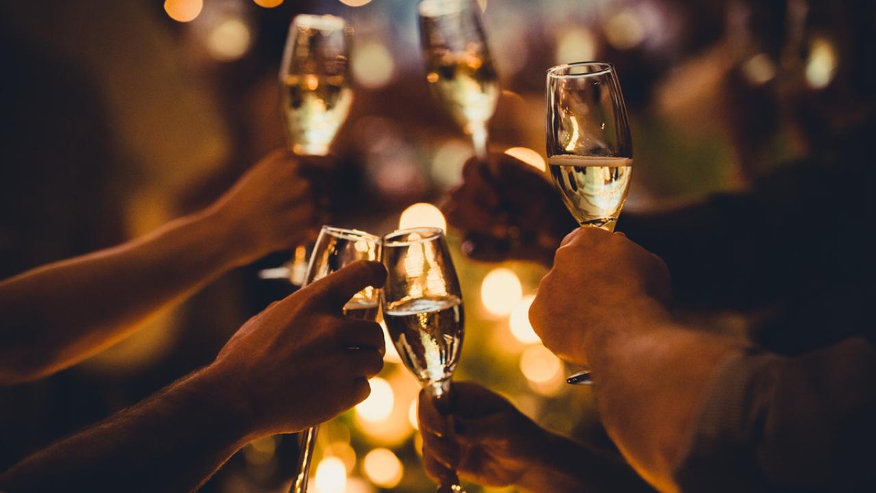 multiple people hold of champagne glasses in a celebratory toast