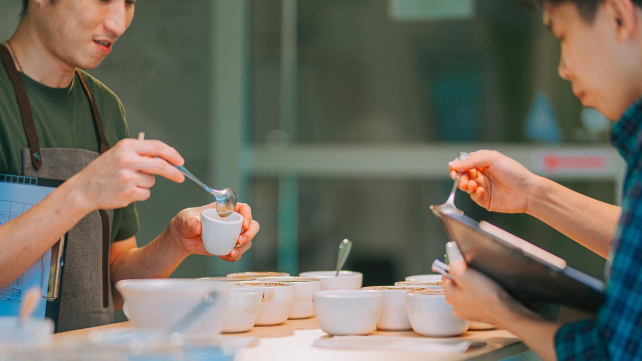 two baristas prepare for a coffee cupping tasting scope
