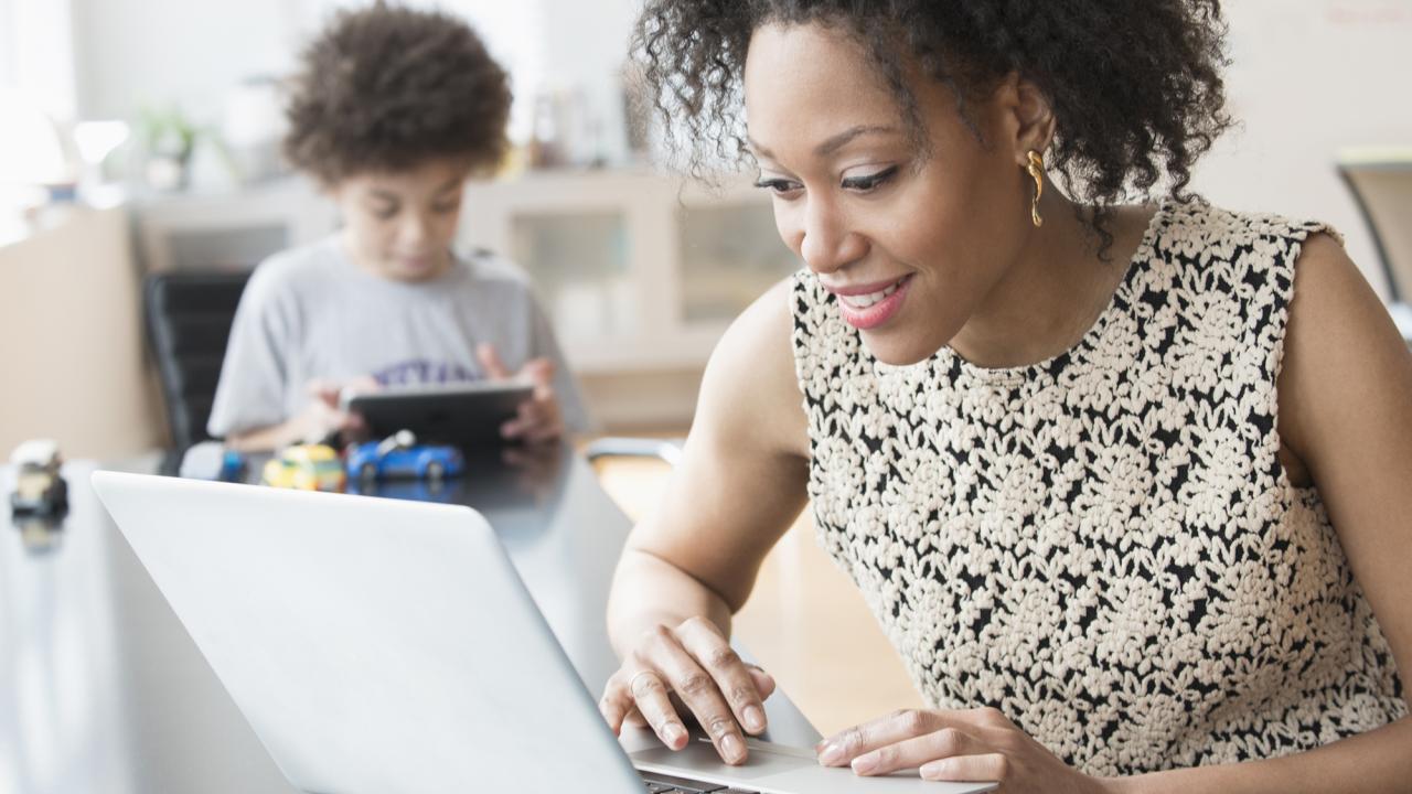 mom on laptop with son in background on tablet