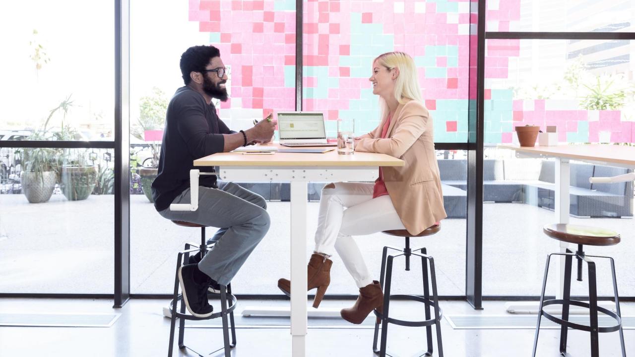 A man and woman sit at a cafe table talking. 