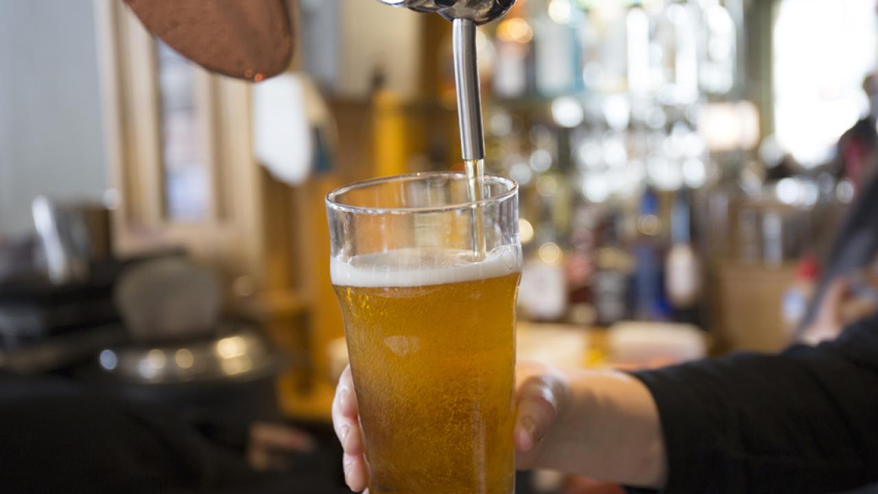 bar tender filling glass with beer at tap