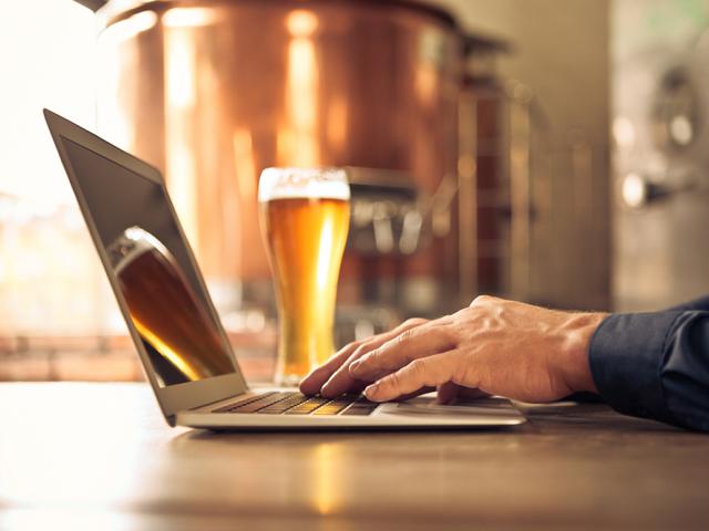 person on computer with beer