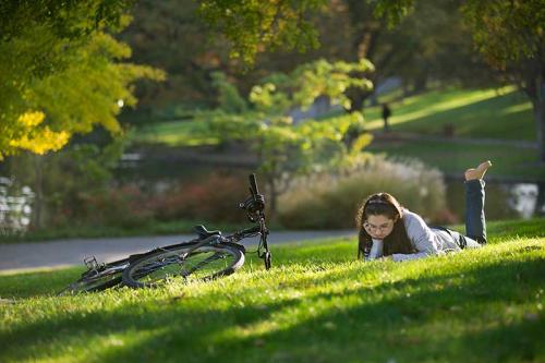 student studying on grass at UC Davis Arboretum