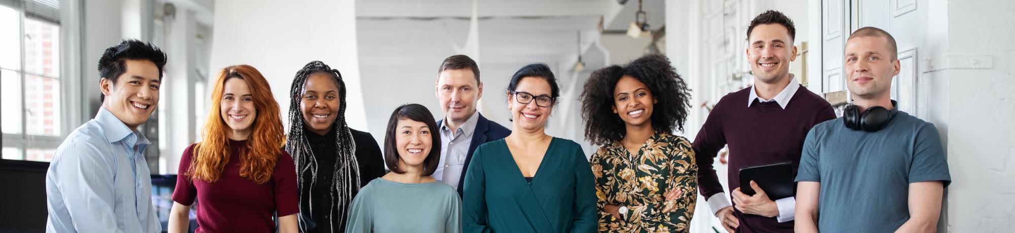 a group of people of varied races, genders and ages standing in a line