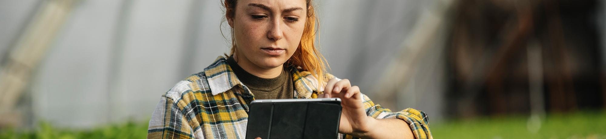 woman working on a tablet in a greenhouse