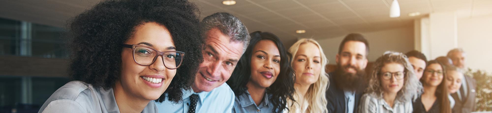 group of smiling people sitting in a line facing camera